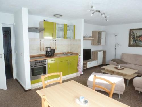 cocina y sala de estar con armarios amarillos y mesa en Ferienwohnung Wieker Bodden, en Dranske