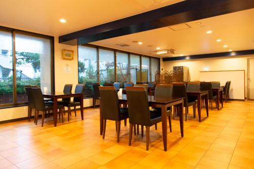 a dining room with tables and chairs and windows at Tabist Sasebo Palace Hotel in Sasebo