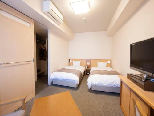 pokój hotelowy z 2 łóżkami i telewizorem z płaskim ekranem w obiekcie Dormy Inn Tsu w mieście Tsu