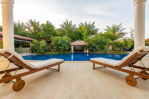 a patio with two chairs and a swimming pool at Villa Lazuli - Saadiyat Island - A one-of-a-kind stay, with jacuzzi and pool - limited to 12 in Abu Dhabi