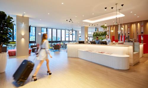 a woman walking through a lobby with luggage at Holiday Inn Express Brisbane Central by IHG in Brisbane
