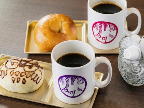 drei Tassen Kaffee und ein Donut auf einem Tablett in der Unterkunft Hotel Wing International Select Ikebukuro in Tokio