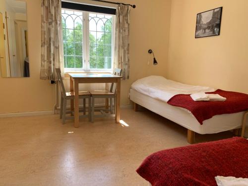 a bedroom with a bed and a table and a window at Leksands Folkhögskola in Leksand