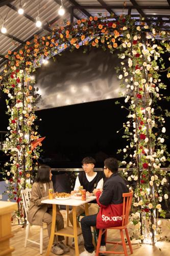 a group of people sitting at a table in front of a large arch at Anh Trang Homestay in Da Lat