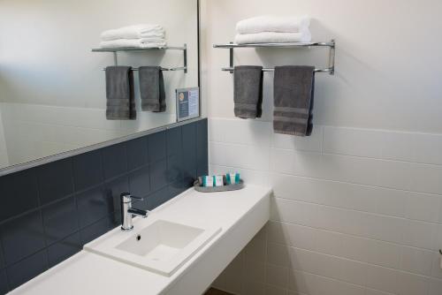 a bathroom with a sink and a mirror and towels at The Heritage Bendigo in Bendigo