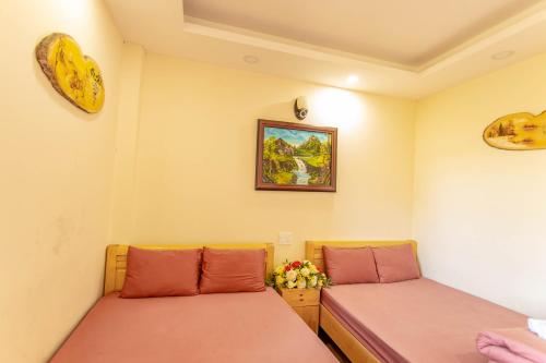 a room with two beds and a picture on the wall at Anh Trang Homestay in Da Lat