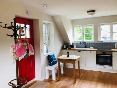 a kitchen with a red door and a table at Katjas Kate Mansarde in Prerow
