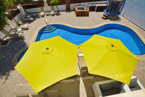 two yellow umbrellas next to a swimming pool at Seafront Protaras Villas in Protaras