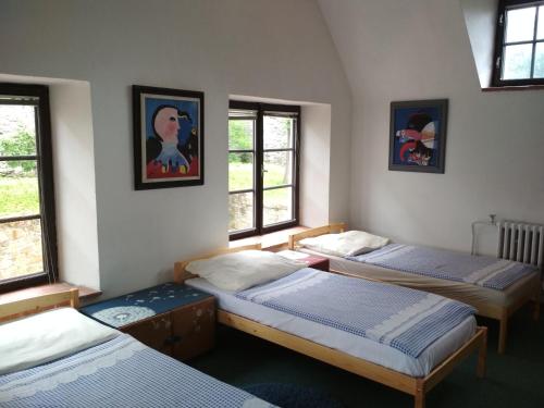 three beds in a room with three windows at Penzion U Tkadlen in Jindřichŭv Hradec