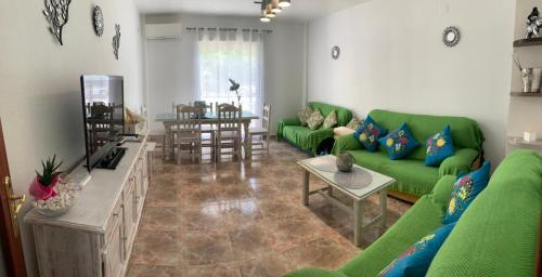 ein Wohnzimmer mit einem grünen Sofa und einem Tisch in der Unterkunft Casa Vista Nevada in Güéjar-Sierra