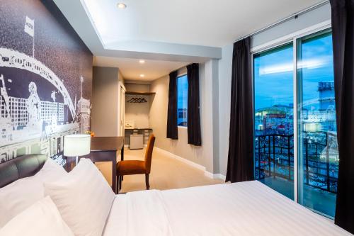 バンコクにあるAt Hua Lamphong Hotelのベッド、デスク、窓が備わるホテルルームです。