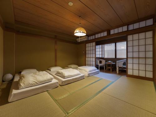 ein Schlafzimmer mit 2 Betten in einem Zimmer mit einem Tisch in der Unterkunft 今日都 Kyoto Guesthouse in Kyoto