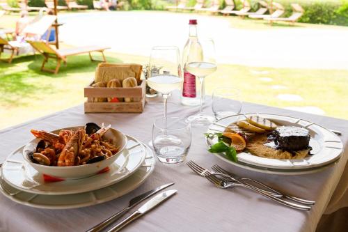 a table with two plates of food and wine glasses at Hotel Aldiola Country Resort in Sant Antonio Di Gallura