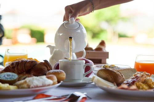 a person is pouring coffee into a cup on a table at Hotel Aldiola Country Resort in Sant Antonio Di Gallura