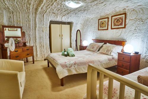 a bedroom with a bed and a dresser and a staircase at Underground Bed & Breakfast in Coober Pedy