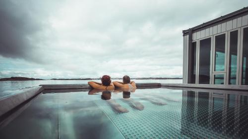dos mujeres sentadas en el borde de una piscina en Gullmarsstrand Hotell & Konferens, en Fiskebäckskil