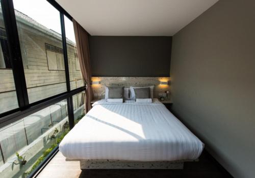 a bedroom with a bed and a large window at V Varee Bangkok in Bangkok