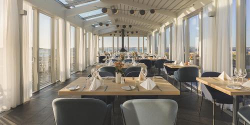 a dining room with tables and chairs and windows at Gullmarsstrand Hotell & Konferens in Fiskebäckskil