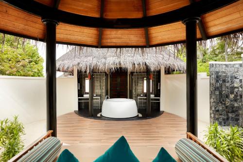 a patio with chairs and a tub on a house at Sun Siyam Iru Fushi with Free Transfer in Manadhoo
