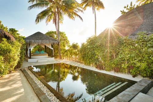 a pool with a gazebo and palm trees at Sun Siyam Iru Fushi with Free Transfer in Manadhoo
