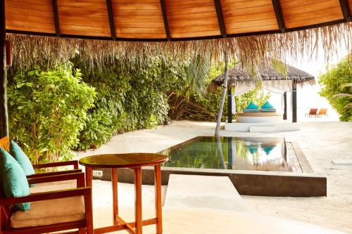a patio with a table and a swimming pool at Sun Siyam Iru Fushi with Free Transfer in Manadhoo