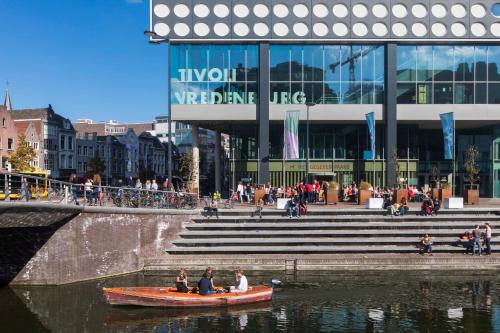 a group of people in a boat on a river in front of a building at Crowne Plaza Utrecht - Central Station by IHG in Utrecht