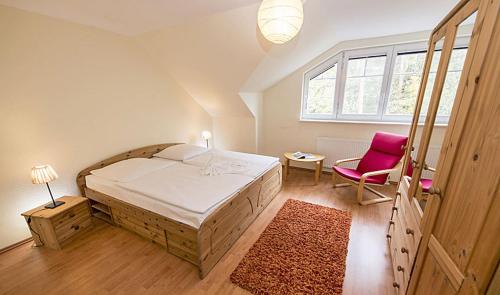 1 dormitorio con 1 cama grande y 1 silla rosa en Fewo Meeresrauschen, en Thiessow