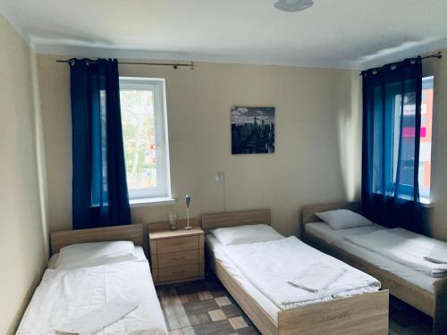 2 łóżka w pokoju z niebieskimi zasłonami w obiekcie Pokoje Goscinne ATENA w mieście Gubin