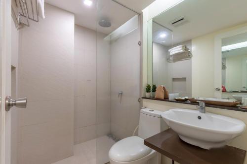 a bathroom with a sink and a toilet and a mirror at Selah Garden Hotel Manila in Manila