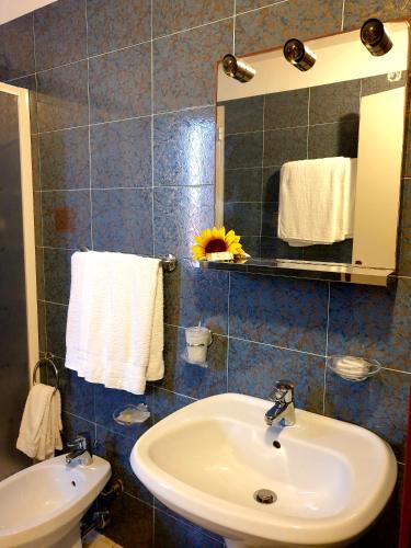 a bathroom with a sink and a mirror and towels at Riccio Hotel in La Maddalena