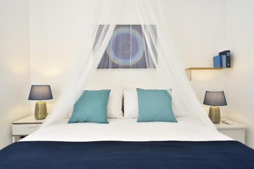 a bedroom with a white bed with blue pillows at CASA BLANCA A 2 PASSI DEL MARE Santa Maria del Focallo in Santa Maria Del Focallo