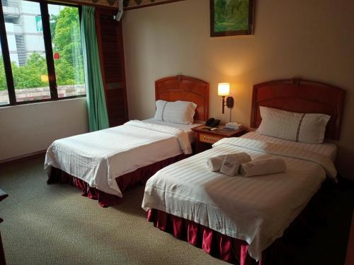 Cette chambre comprend 2 lits et une fenêtre. dans l'établissement Hotel Deleeton, à Kota Kinabalu