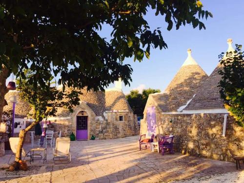 un edificio de piedra con sillas y una puerta púrpura en I MaTrulli, en Cisternino