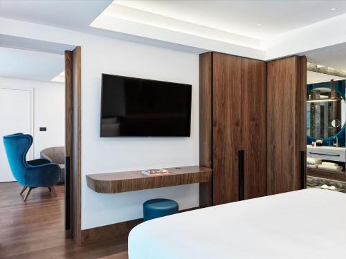 a bedroom with a bed and a tv on a wall at Athens Capital Center Hotel - MGallery Collection in Athens