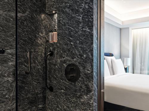 a bathroom with a shower and a bed in a room at Athens Capital Center Hotel - MGallery Collection in Athens