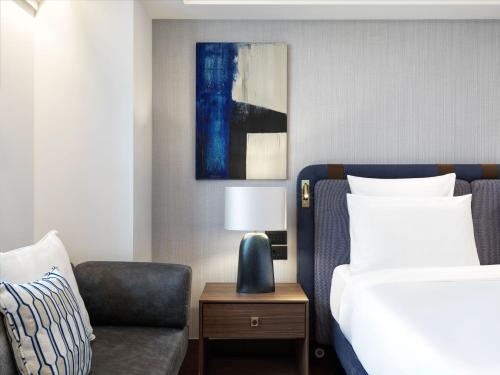 a bedroom with a bed and a couch and a chair at Athens Capital Center Hotel - MGallery Collection in Athens