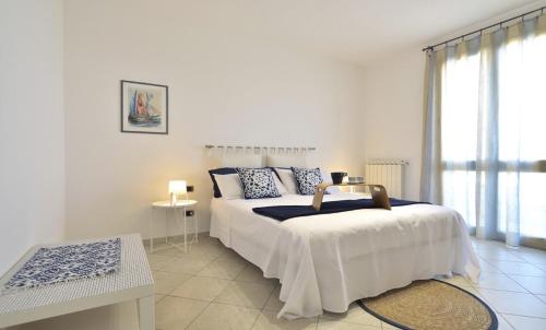 a white bedroom with a bed and a window at CASA DEL FARO PORTOPALO in Portopalo