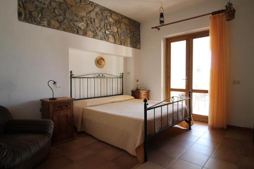 een slaapkamer met een bed, een bank en een raam bij MacchiaPiana in Scansano