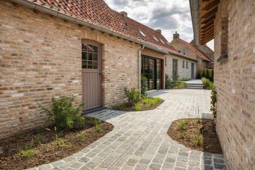 a brick building with a walkway between two buildings at 't Goed ter Fintele in Lo-Reninge