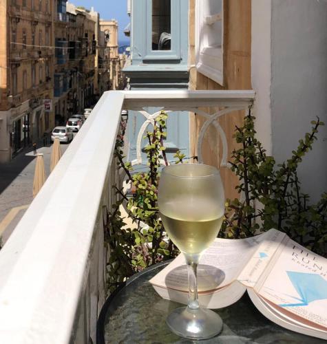 a glass of wine sitting on a table on a balcony at Merchants Street Valletta Apartment in Valletta