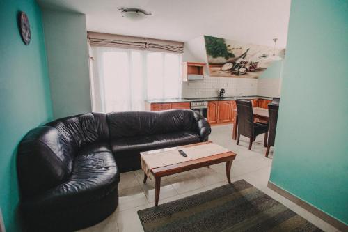 a living room with a leather couch and a coffee table at Ötösfogat Panzió in Siófok