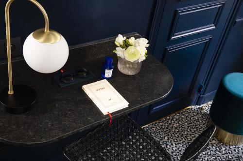 a table with a lamp and a book and flowers on it at Hôtel Gramont in Paris