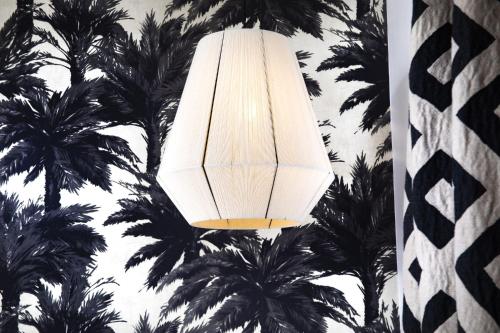 a white light hanging from a wall with palm trees at Hôtel Gramont in Paris