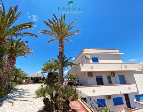 un edificio con palmeras delante en Le Palme Vacanze, en Trappeto