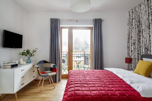 ザコパネにあるApart-Center Pod Orłem IIのベッドルーム1室(赤いベッド1台、デスク、窓付)