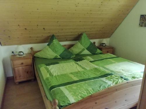 a bedroom with a bed with green sheets and pillows at Ferienwohungen im Kuchersbach in Hornberg