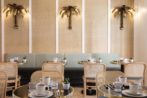 a restaurant with tables and chairs and palm trees at Hôtel Gramont in Paris