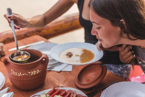 a woman sitting at a table with plates of food at Rafting Center Drina Tara in Bastasi