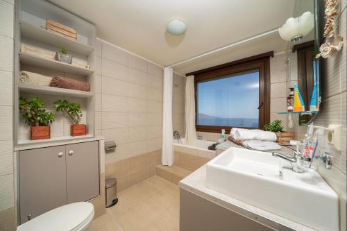 a bathroom with a sink and a toilet and a window at Villa Kandia in Ayia Evfimia