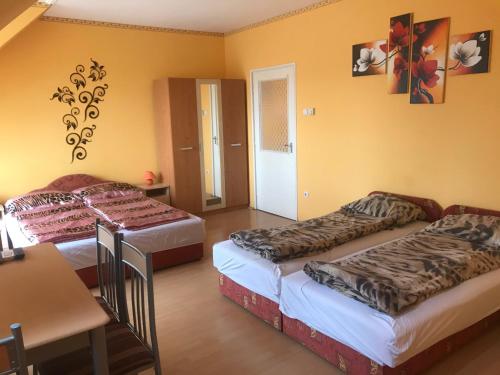 2 łóżka w pokoju z żółtymi ścianami w obiekcie Apartman Sas 6 w Hajduszoboszlo